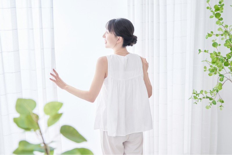 カーテンを開ける女性のイメージ