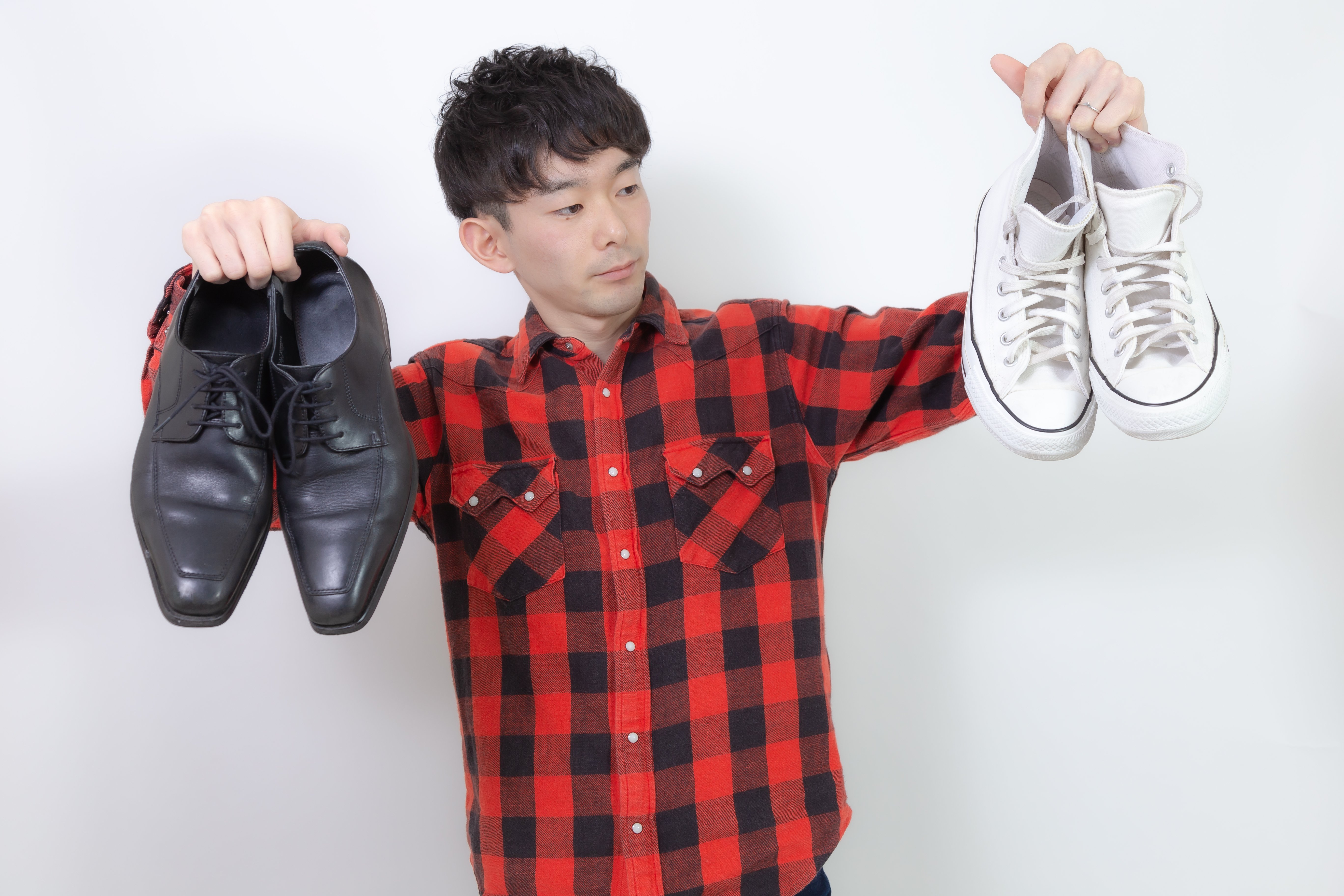 革靴とスニーカーを見比べる場面。会う場所や服装に合う足元を選びます。