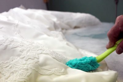 刺繍のある白い生地を部分的に扱う工程。繊細な意匠にも配慮します。