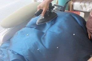 丸みのある台を使った手仕上げ。ドレスの立体感に合わせて形を整えます。