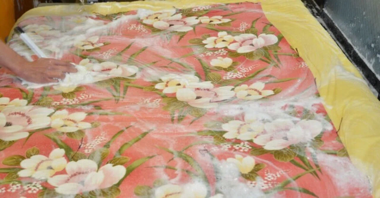 花柄の布団を広げ、泡を使い手作業で洗っている工程